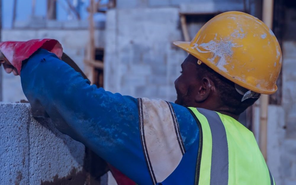 Construction worker in a hard hat and high-visibility vest building a wall